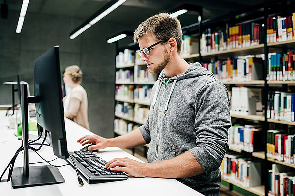 Student arbeitet in der Bibliothek am PC-Bildschirm