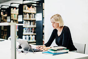 Eine Studentin sitzt an einem Arbeitsplatz in der Bibliothek