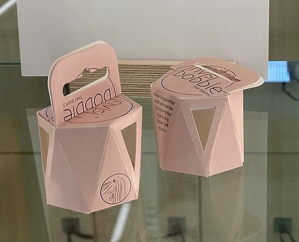 Sechseckige Pappschachteln in Rosa, raffiniert gefaltet, mit Henkel.